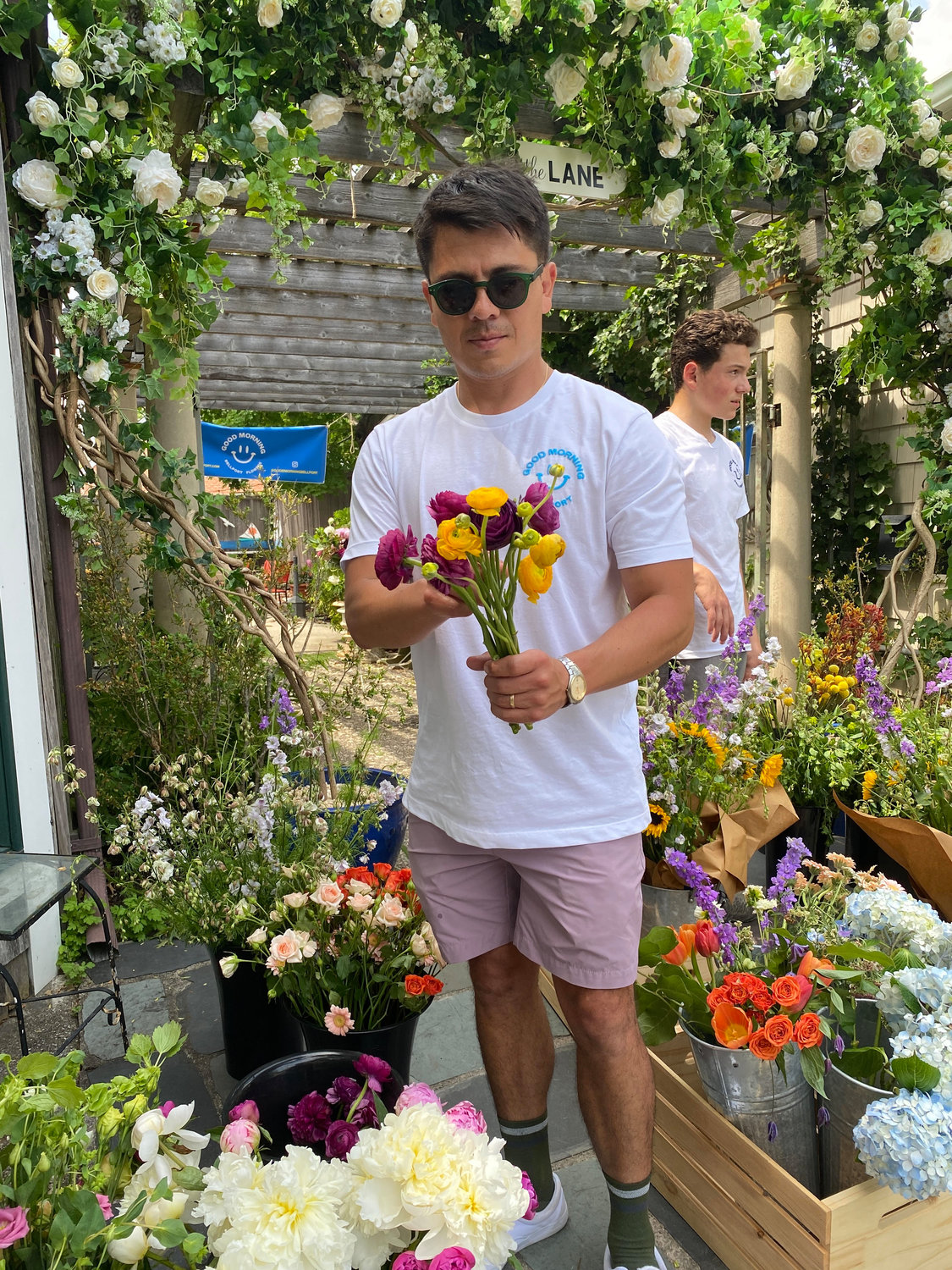 Fabian Bernal, owner of Good Morning Bellport, designs a floral assortment for a last-minute customer. In the background is Max Yablon.